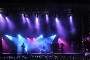 Concerts - Concert Stage Lit Up With Blue Pink and Purple Lights And Smoke While Playing to a Full Audience